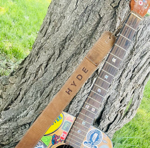HYDE Guitar Strap attached to a cool Guitar leaning up against a tree 